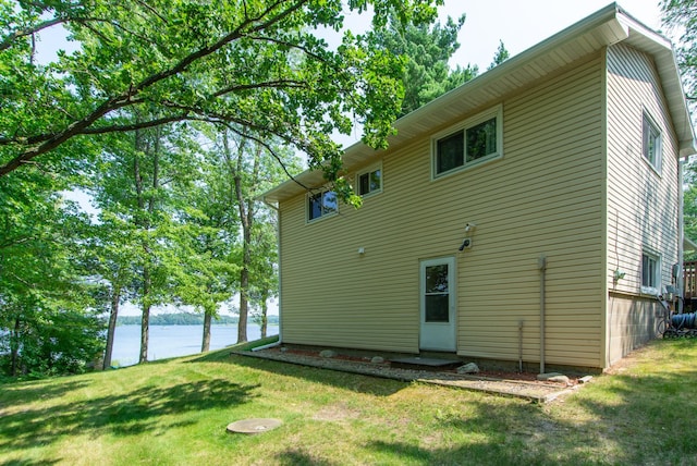 rear view of house featuring a water view and a yard