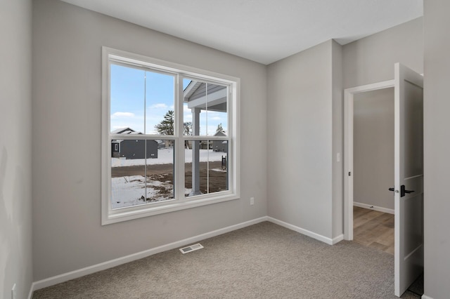 unfurnished room with carpet flooring, visible vents, and baseboards