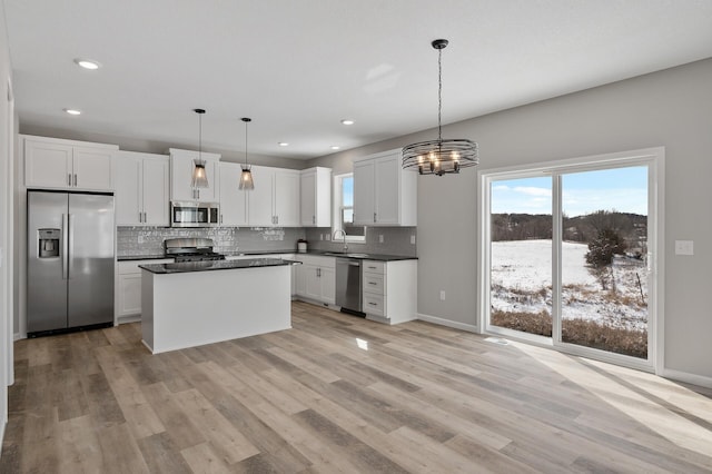 kitchen with light wood finished floors, appliances with stainless steel finishes, dark countertops, and decorative backsplash