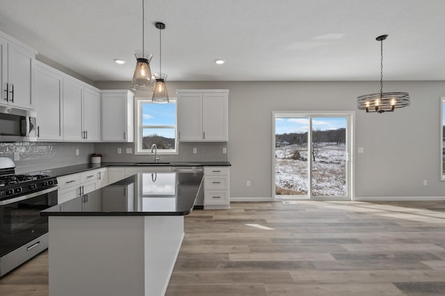 kitchen featuring stainless steel appliances, dark countertops, decorative backsplash, and a healthy amount of sunlight