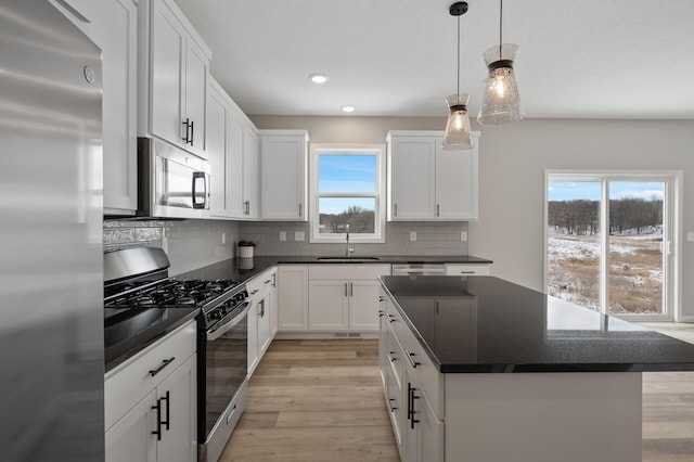 kitchen with tasteful backsplash, light wood-style flooring, a kitchen island, stainless steel appliances, and a sink