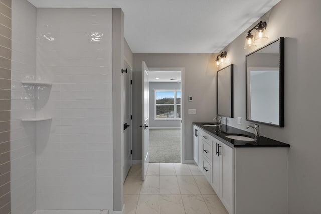 bathroom featuring marble finish floor, a sink, baseboards, and double vanity