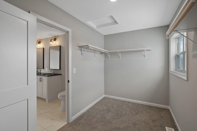 walk in closet with marble finish floor and a sink