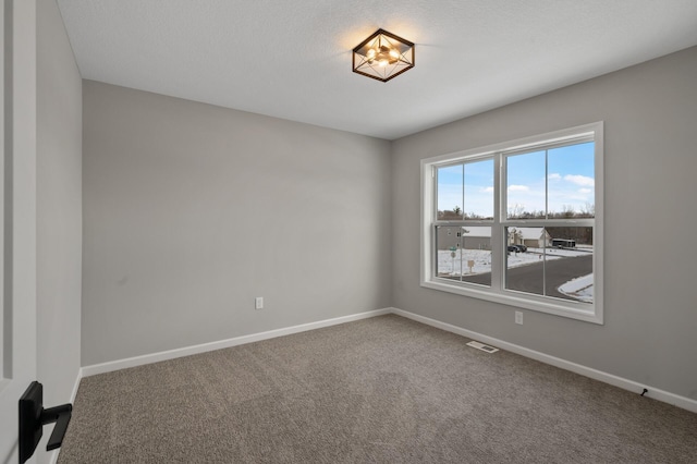 spare room with carpet, visible vents, a textured ceiling, and baseboards