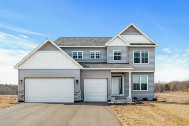 view of front of home with board and batten siding, roof with shingles, a garage, and aphalt driveway