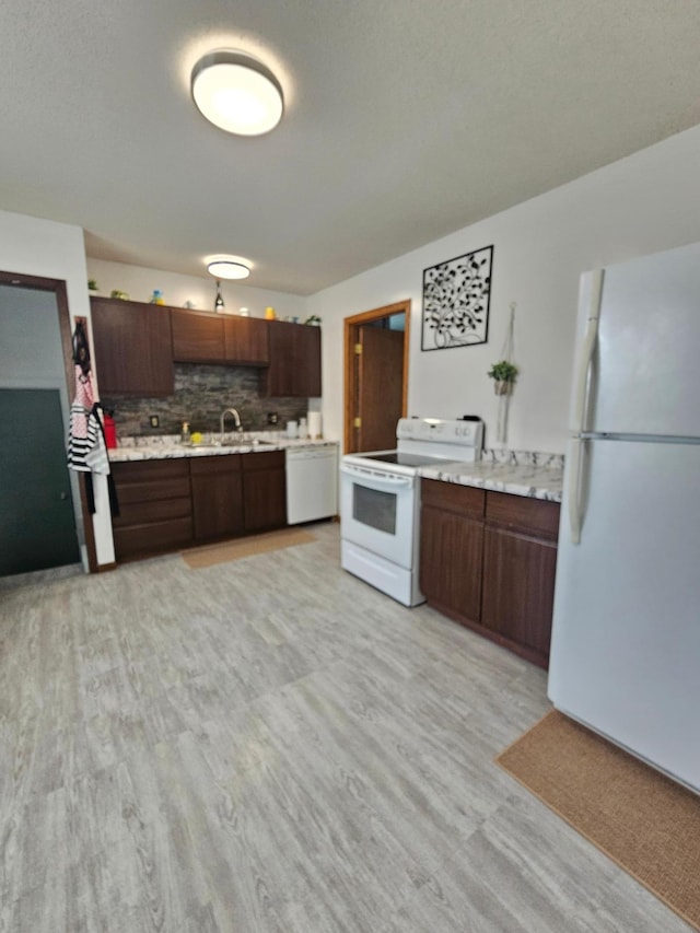 kitchen featuring white appliances, tasteful backsplash, light wood-style flooring, light countertops, and a sink