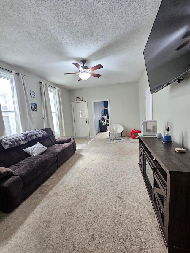 living room featuring a ceiling fan, carpet flooring, and a textured ceiling