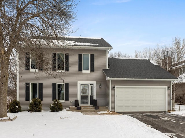 colonial house featuring a garage, driveway, and a shingled roof