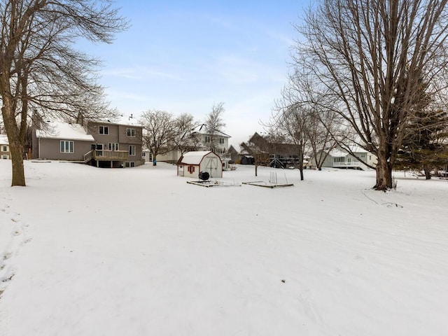 yard covered in snow featuring a storage unit and an outdoor structure