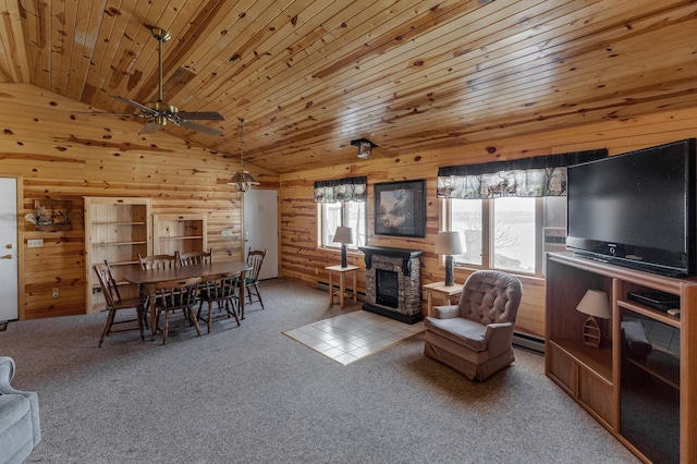 carpeted living area with wood ceiling, baseboard heating, vaulted ceiling, a stone fireplace, and wood walls