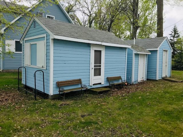 rear view of property featuring an outbuilding and a yard