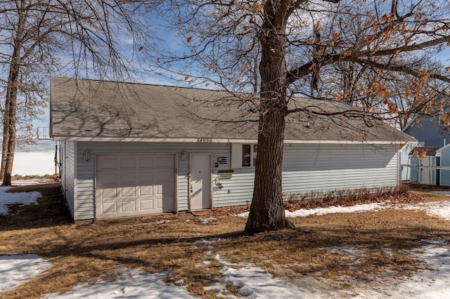 view of front of house featuring a garage, driveway, and a shingled roof