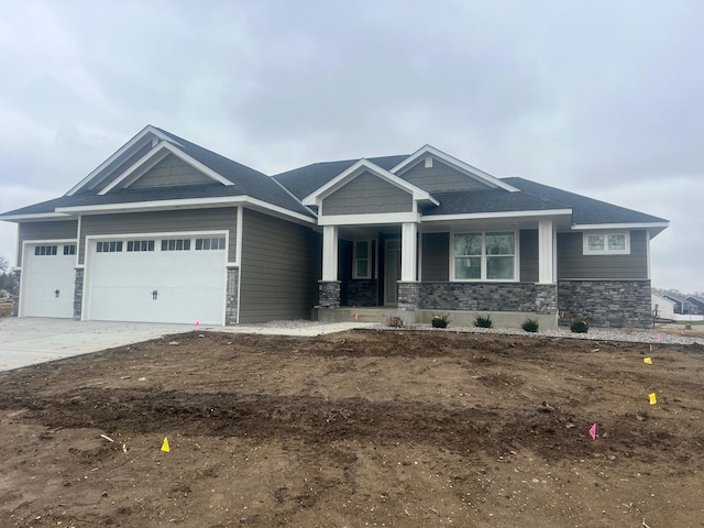 craftsman-style house with a garage, stone siding, and concrete driveway