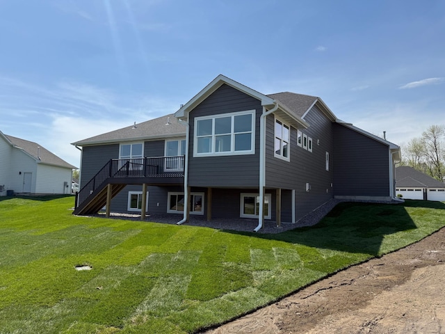 back of property with stairs, a deck, and a lawn