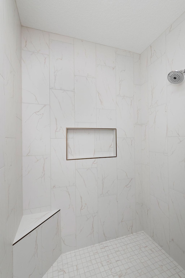 full bath featuring a tile shower and a textured ceiling