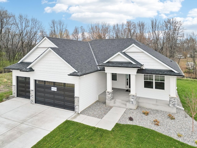 modern farmhouse style home featuring concrete driveway, stone siding, roof with shingles, an attached garage, and covered porch