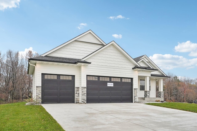 craftsman inspired home featuring an attached garage, driveway, stone siding, roof with shingles, and a front yard