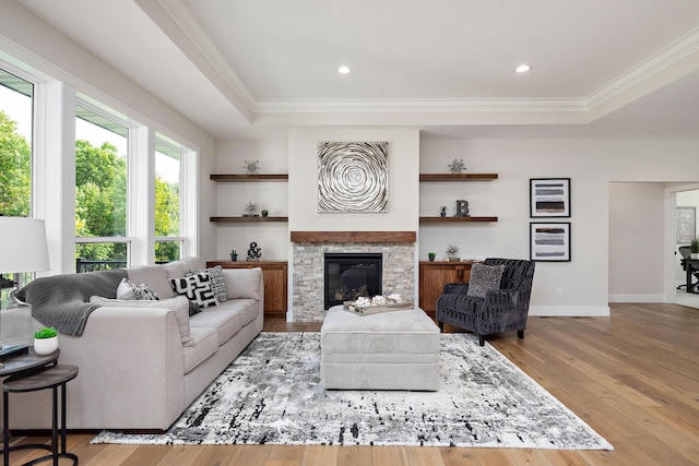 living area with wood-type flooring, a tray ceiling, and ornamental molding