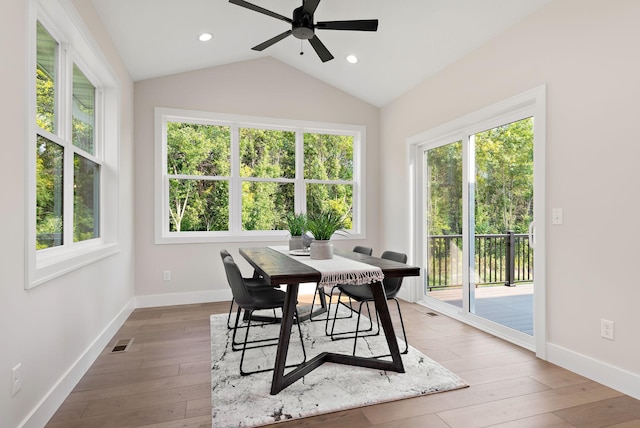 dining space with wood-type flooring, visible vents, vaulted ceiling, and baseboards