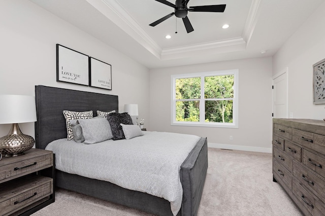 bedroom featuring baseboards, a raised ceiling, light colored carpet, and crown molding