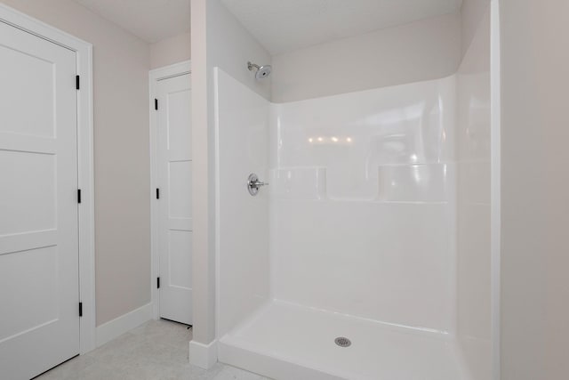 bathroom with a shower stall, baseboards, and a textured ceiling