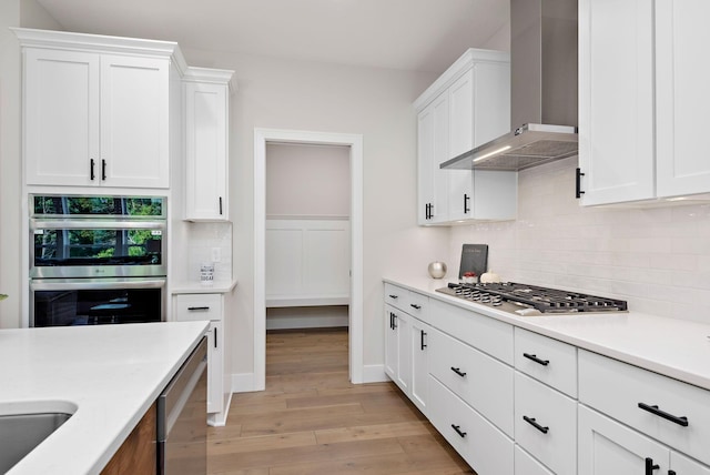 14196 77th Ln NE, Otsego, MN 55330 - kitchen with light wood finished floors, white cabinetry, decorative backsplash, wall chimney exhaust hood, and stainless steel appliances