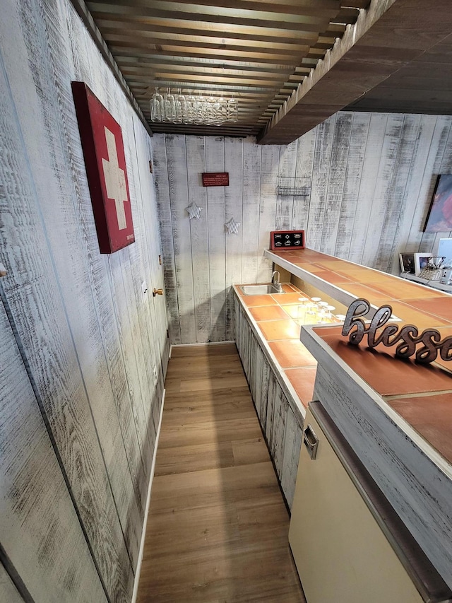 bar featuring wood walls, a sink, and wood finished floors