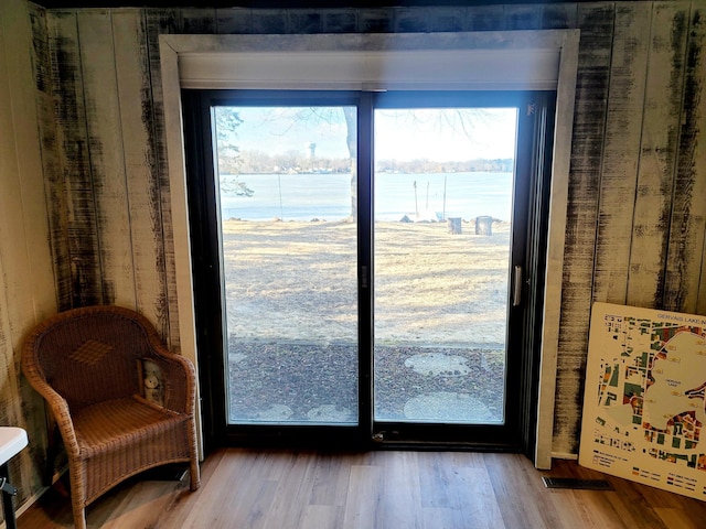 doorway featuring a water view, a healthy amount of sunlight, and wood finished floors