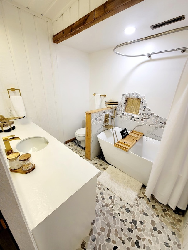 full bath with visible vents, a freestanding bath, toilet, and vanity