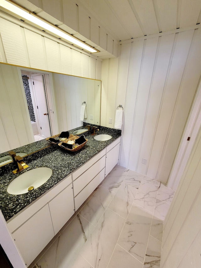 full bath featuring a sink, double vanity, and marble finish floor