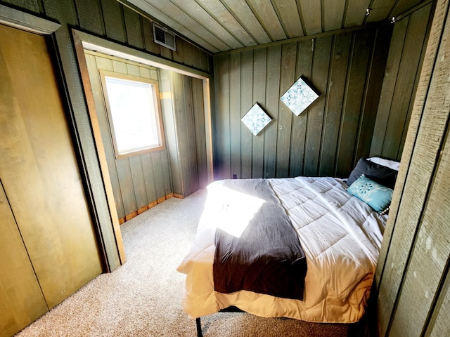 carpeted bedroom with wood walls and wooden ceiling