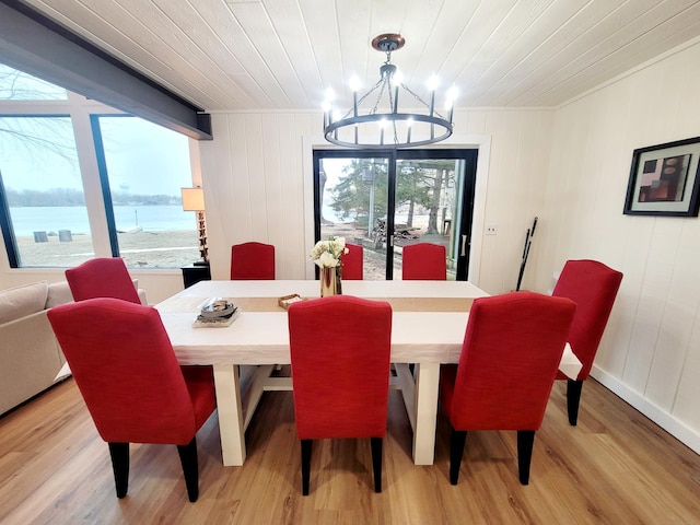 dining space with light wood-style flooring, wood ceiling, a water view, and a chandelier