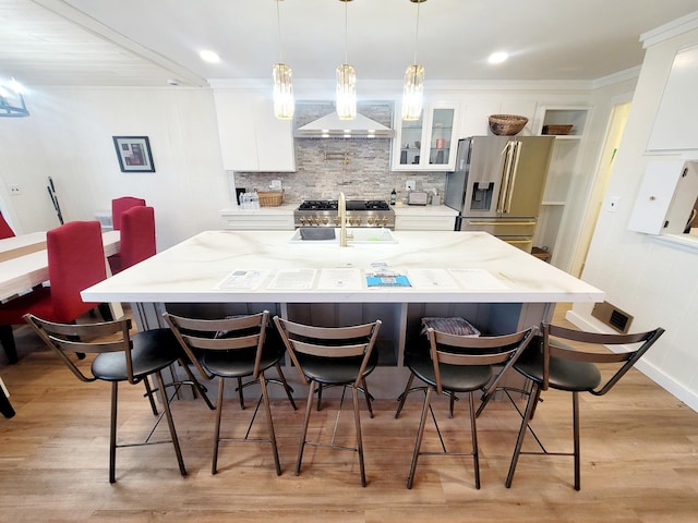 kitchen featuring ventilation hood, a breakfast bar area, white cabinetry, tasteful backsplash, and stainless steel refrigerator with ice dispenser