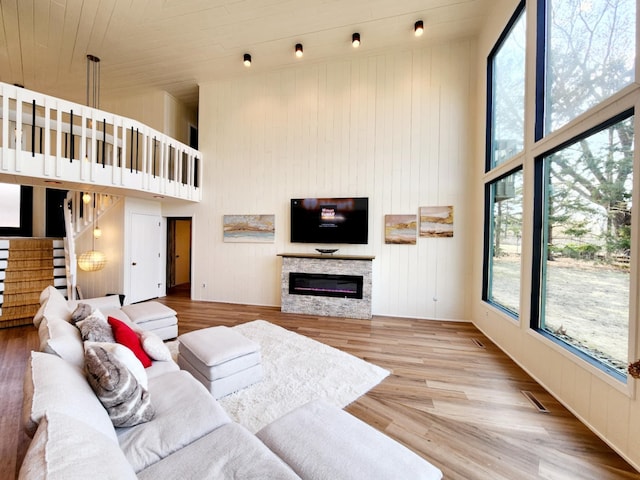 living room with stairs, a stone fireplace, a wealth of natural light, and a towering ceiling