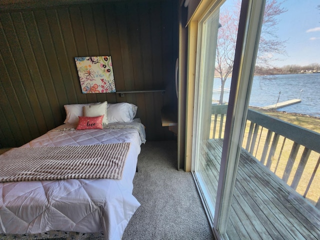 bedroom featuring wooden walls, a water view, and carpet