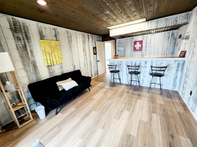 interior space with wooden walls, wood ceiling, a bar, and wood finished floors
