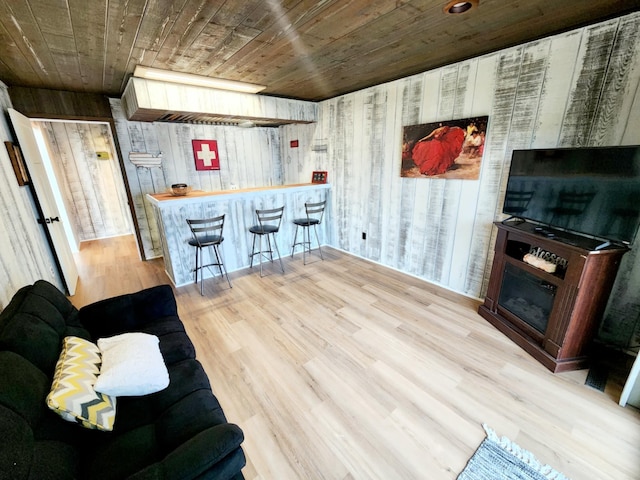 living room featuring a bar, wood ceiling, wood finished floors, and wooden walls
