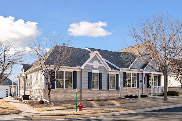 view of front facade with a shingled roof, brick siding, and central AC unit