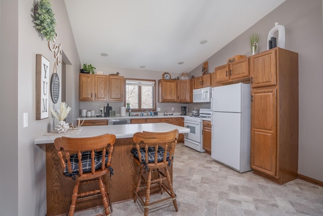 kitchen featuring lofted ceiling, light countertops, white appliances, a peninsula, and a kitchen breakfast bar