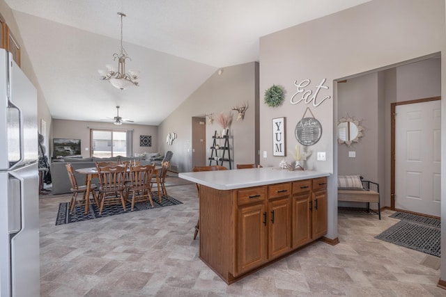 kitchen with brown cabinets, open floor plan, freestanding refrigerator, vaulted ceiling, and light countertops