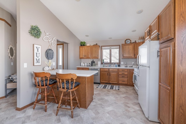 kitchen with a breakfast bar area, light countertops, freestanding refrigerator, dishwasher, and a peninsula