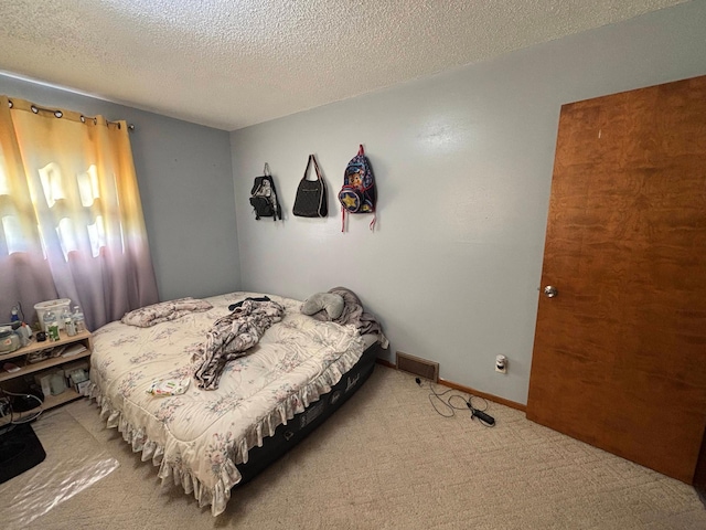 bedroom with carpet, visible vents, a textured ceiling, and baseboards