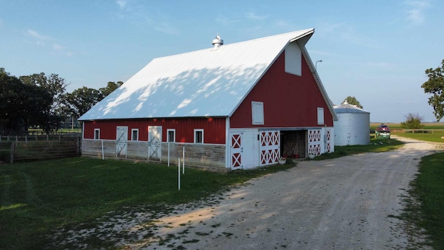 view of home's exterior featuring an outbuilding, metal roof, fence, a barn, and a garage