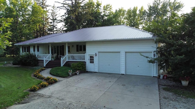 ranch-style home featuring driveway, metal roof, an attached garage, covered porch, and a front yard