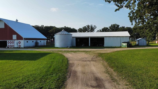 view of pole building featuring dirt driveway and a lawn