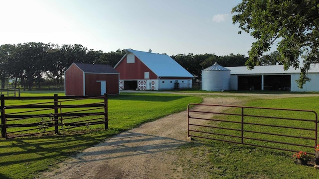 view of gate featuring an outbuilding, a yard, and fence