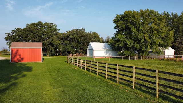 view of yard with a pole building, a rural view, an outdoor structure, and fence