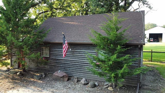 view of side of property with roof with shingles and a detached garage