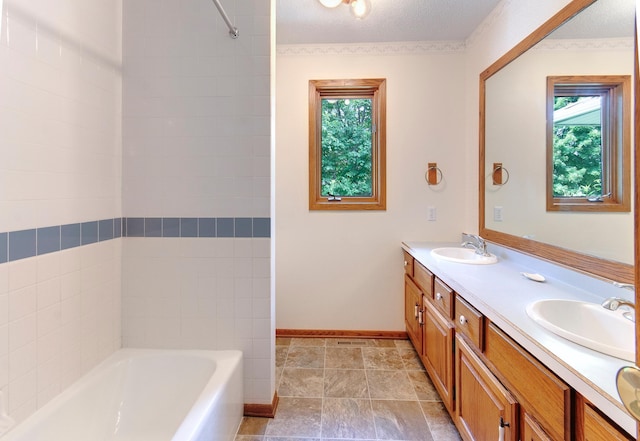 bathroom featuring a wealth of natural light, a tub, and a sink