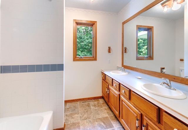 bathroom with a tub to relax in, a wealth of natural light, and a sink